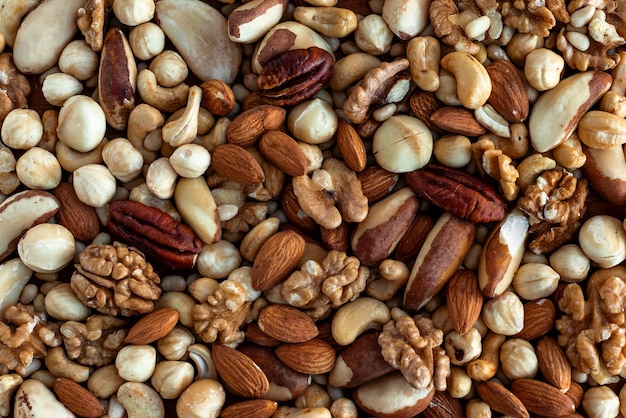 Photo different tasty nuts in a heap. nuts background. walnut, pecan, almonds, hazelnuts, macadamia and cashews