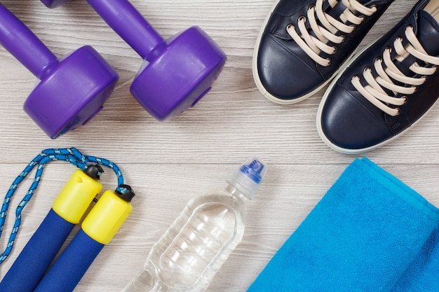 Different tools for fitness with bottle of water in room or gym on grey floor