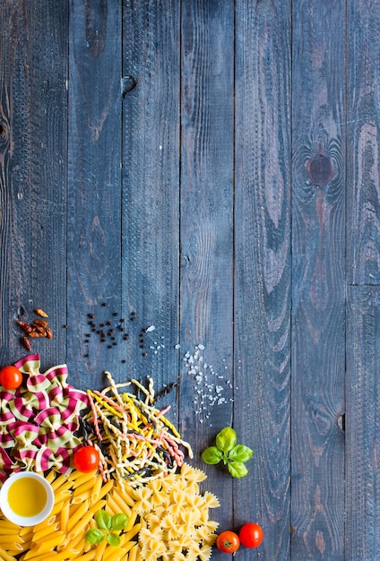 Different type of italian pasta on a wooden background, free space for text.