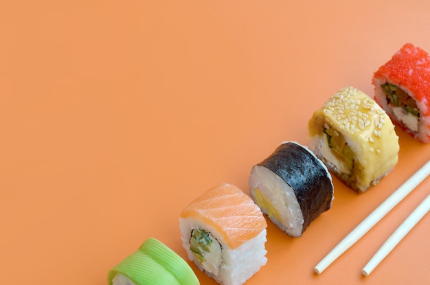 Different types of asian sushi rolls on orange background Minimalism top view flat lay with Japanese food