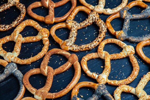 Different types of baked bagels with seeds on a black background