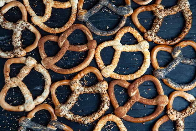 Different types of baked pretzels or bagels with seeds on a black background