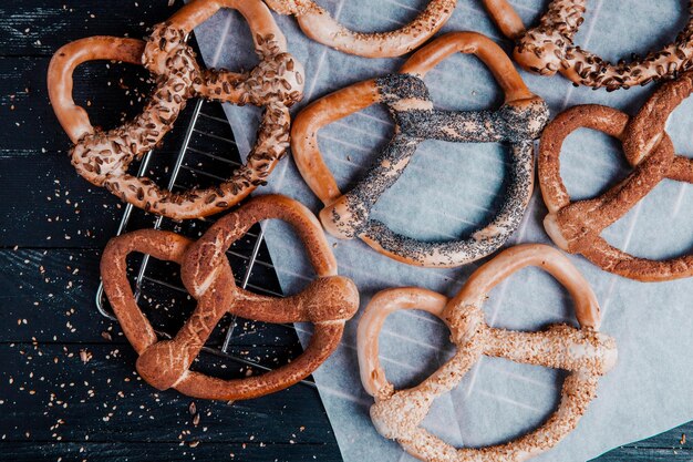 Different types of baked pretzels or bagels with seeds on a black background