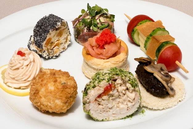 Different types of canapes, placed on white plates, finger food