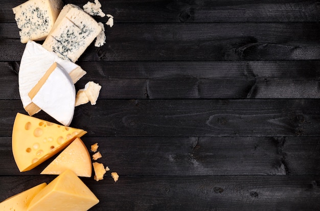 Different types of cheese on black table. Top view