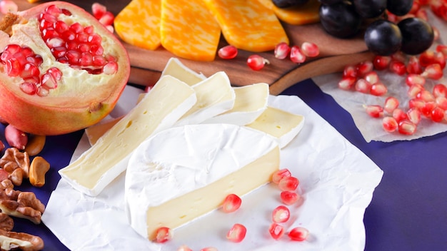 Different types of cheese and fruit Sliced camembert and pomegranate Camembert and grapes