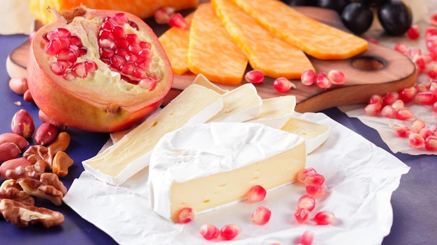 Different types of cheese and fruit Sliced camembert and pomegranate Camembert and grapes