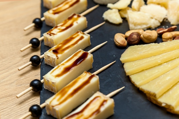 치즈 메이커의 프레젠테이션에서 다양한 종류의 치즈. 블루 치즈가 있는 치즈 플레이트, 견과류가 든 브리, 나무 테이블에 꿀이 있는 최고의 전망.
