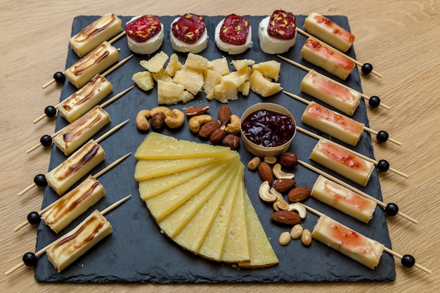 チーズメーカーからのプレゼンテーションでのさまざまな種類のチーズ。ブルーチーズ、ナッツとブリーチーズ、木製のテーブルの上の蜂蜜とチーズプレートの上面図。