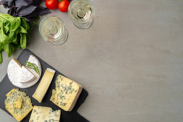 Different types of cheese and wine on gray table