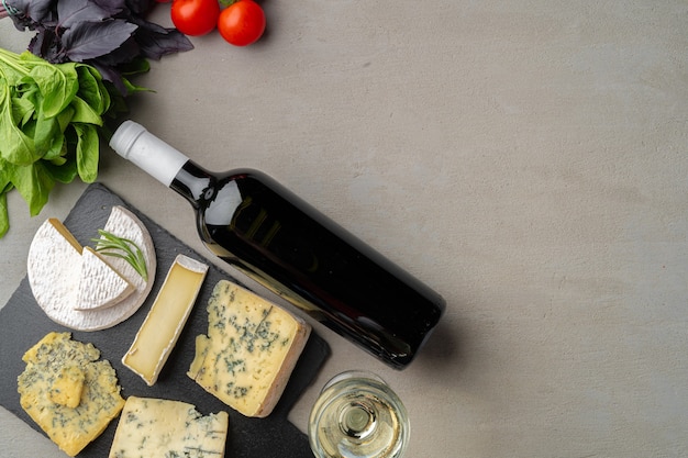 Different types of cheese and wine served on gray table