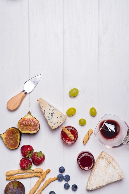 Different types of cheeses with wine glass and fruits