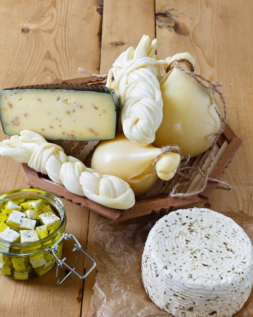 Different types of cheeses on a wooden background. 