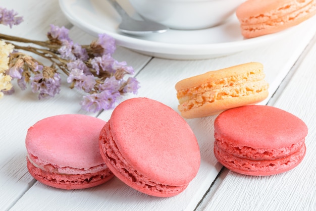 Diversi tipi di colore di amaretti con una tazza di tè caldo su legno bianco