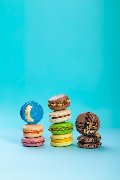 Different types of colorful sweet macaroons dessert on blue background