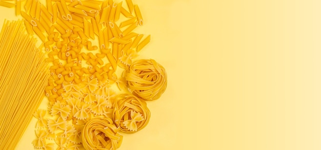 Different types of dry italian pasta in the form of a round frame on a yellow background