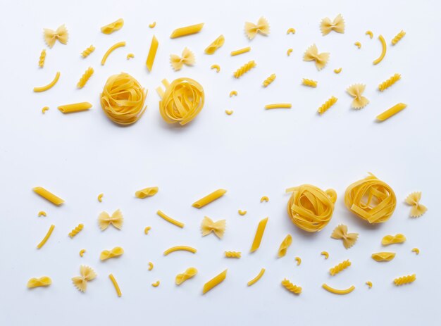 Different types of dry pasta on white.