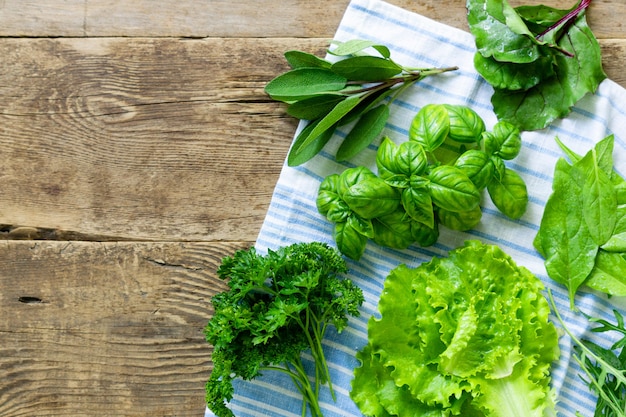 Different types of fresh herbs on old wooden background