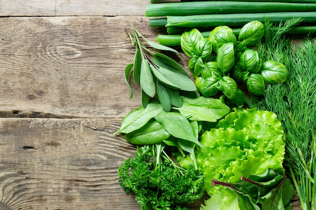 Different types of fresh herbs on old wooden background