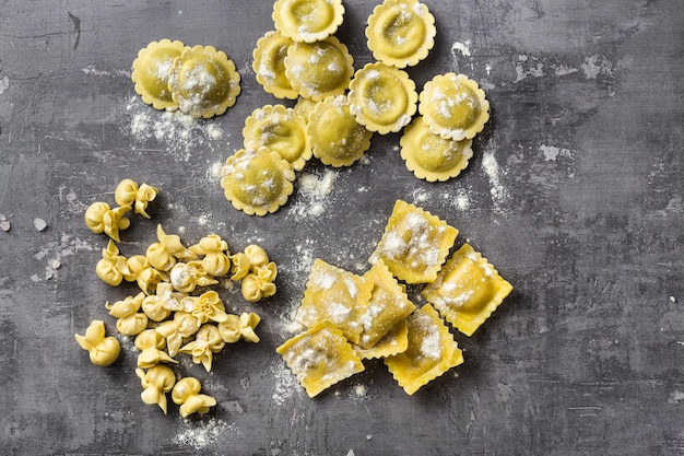 Photo different types of fresh raw italian ravioli on the table with cooking ingredients home kitchen