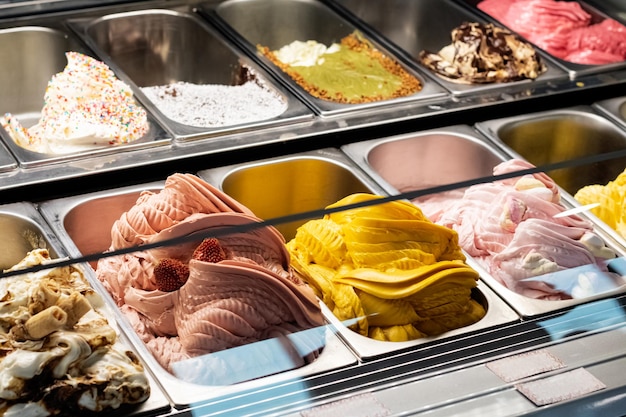 Photo different types of ice cream in containers on store