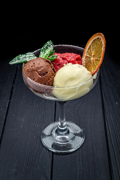 Different types of ice cream in a glass glass on a dark background