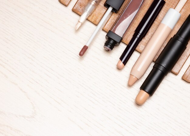 Different types of makeup concealers on white wood table Top view copy space