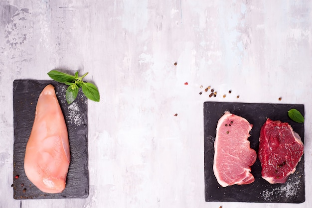 Different types of meat on dark slate cutting board. Lean proteins.