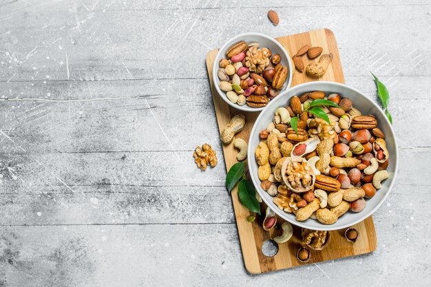 Different types of nuts in bowls with green leaves