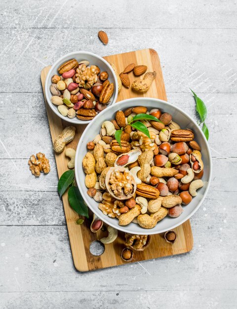 Different types of nuts in bowls with green leaves