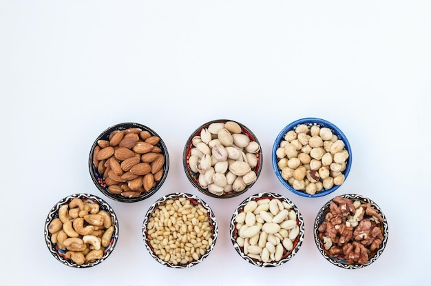 Different types of nuts peanuts pine nut cashews almonds hazelnuts walnuts and pistachios on white background Top view