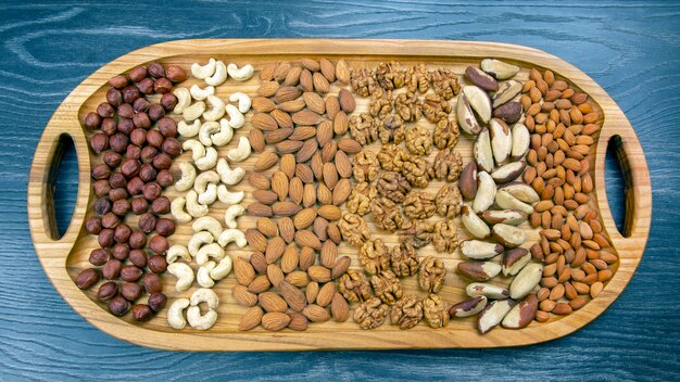 Different types of nuts on a wooden tray on the table. organic vitamin food. hazelnuts and almonds