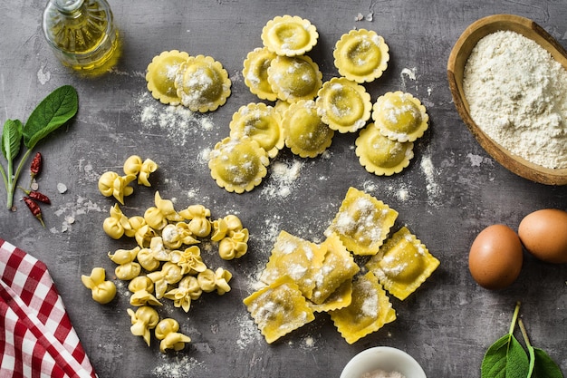 写真 テーブルの上のさまざまな種類の新鮮な生のイタリアのラビオリと、家庭の台所の食材