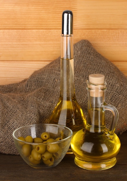 Different types of oil with olives on wooden background