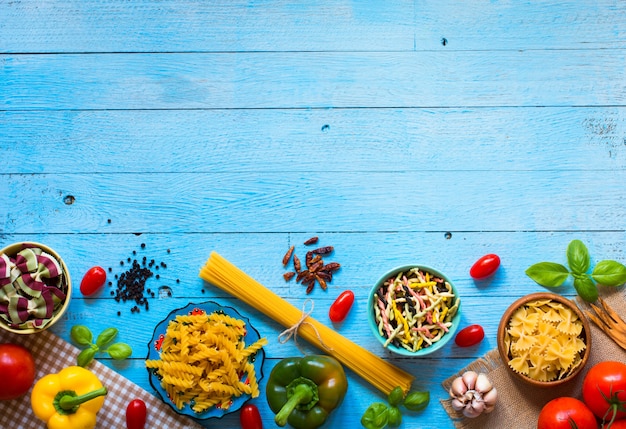 Different types of pasta with various types of vegetables, health or vegetarian concept on a wooden table,  Top view