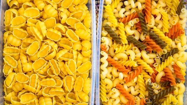 Diversi tipi di pasta grezza italiana gnocchi pasta tricolore in contenitori di plastica trasparenti