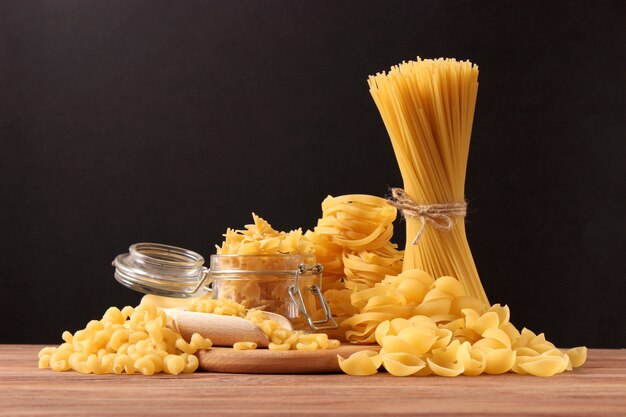 Different types of raw pasta closeup on a colored background