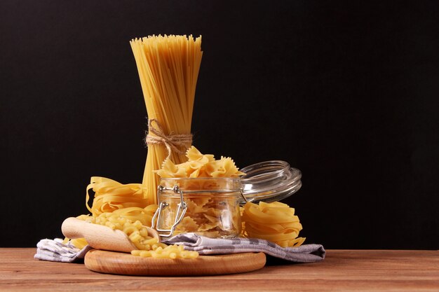 Different types of raw pasta closeup on a colored background