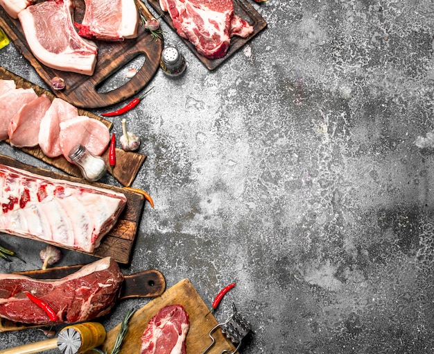 Diversi tipi di carne di maiale cruda e manzo con spezie ed erbe aromatiche. su fondo rustico.