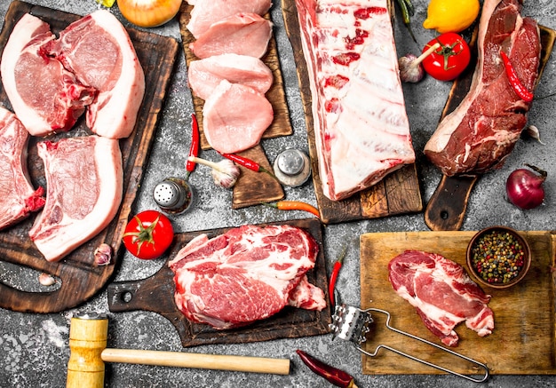 Different types of raw pork meat and beef with spices and herbs.