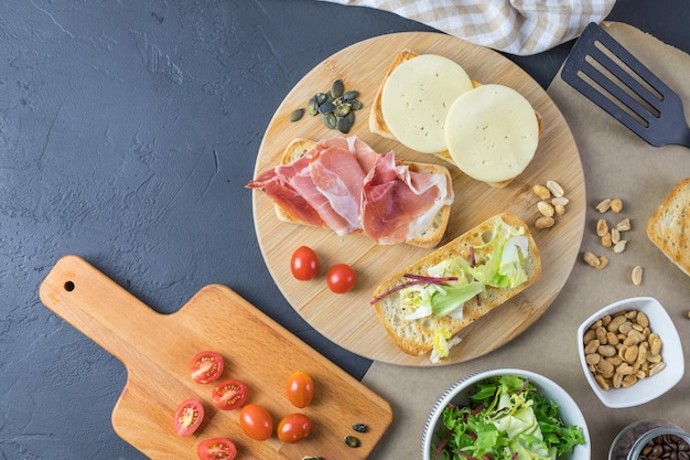 Different types of sandwiches on a wooden board top view Dark background