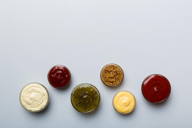 Different types of sauces in bowls on a colored Board Top view various sauces copy space