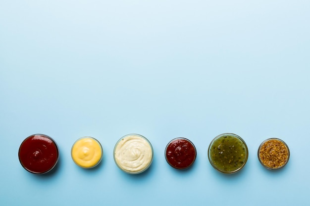 Different types of sauces in bowls on a colored Board Top view various sauces copy space