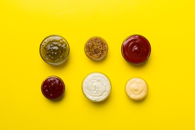 Different types of sauces in bowls on a colored Board Top view various sauces copy space