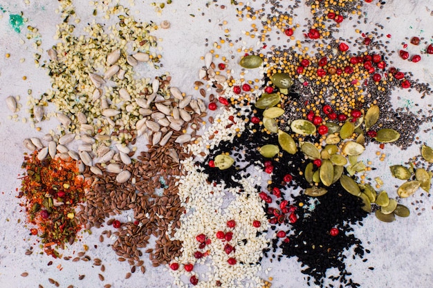 Different types of seeds scattered in the form of an abstract pattern on a white marble surface