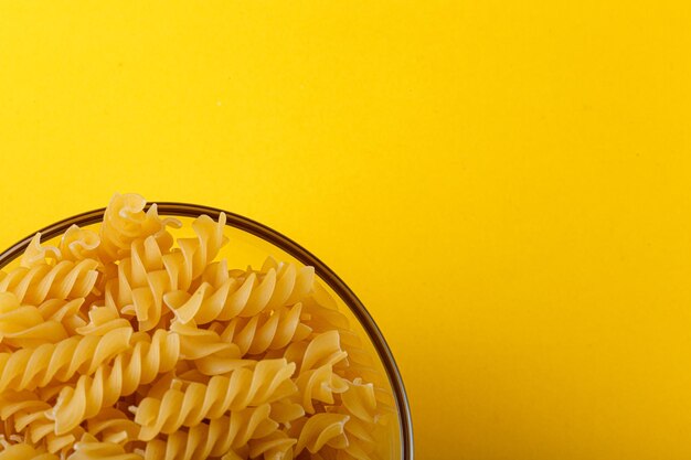 Different types and shapes of dry italian pasta on a yellow background closeup