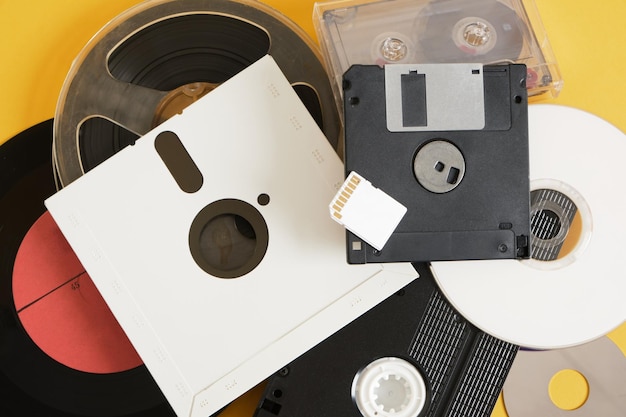 Different types of storage media from the last century against a yellow background retro storage media