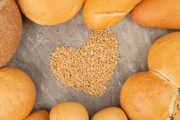 Different types of white and brown bread with seeds on a stone surface 