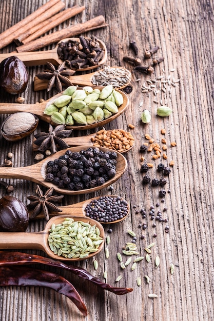 Different types of whole Indian spices in wooden background close-up.