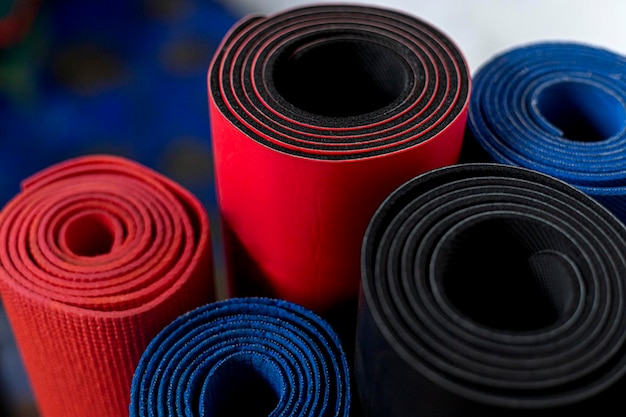 Different types of yoga mats rolled up and standing vertically Yoga and Pilates class concept